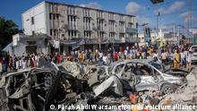 Menschen gehen an zerstörten Autos und Häusern vorbei, wo am Vortag zwei Autobomben an einer belebten Kreuzung in Mogadischu in Somalia eingeschlagen sind. Bei den zwei Selbstmordanschlägen sind nach Angaben des Präsidenten mindestens 100 Menschen getötet und 300 verletzt worden. +++ dpa-Bildfunk +++