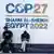 People sit outside a sign for the COP27 climate conference in Sharm El-Sheikh, Egypt
