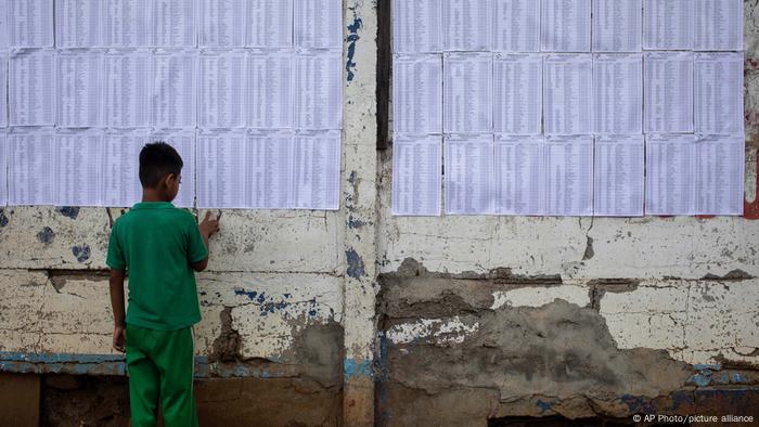 Un niño mira las listas del censo electoral pegadas en un muro ayer en Managua.