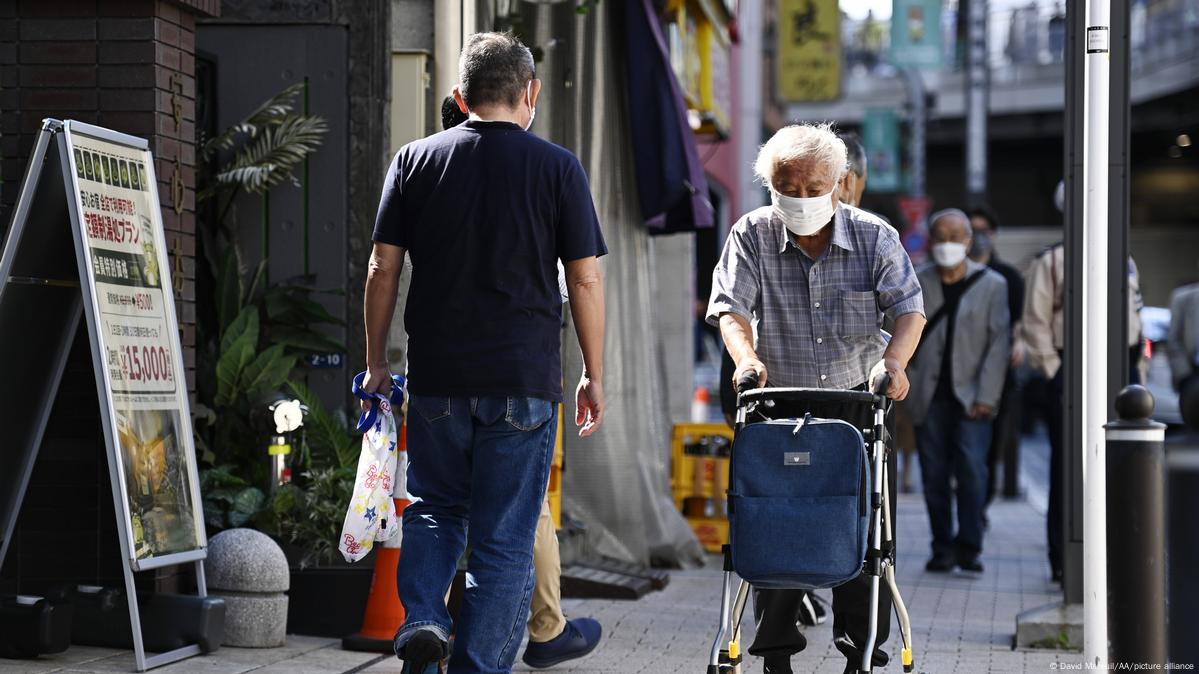An old man pushes a carriage down a street in Tokyo