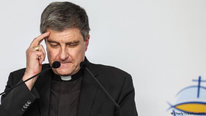 El cardinal arzobispo de Reims, gesticula llevándose la mano a la cabeza ante los micrófonos.