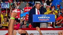TOPSHOT - Former US President Donald Trump wipes the rain from his head as he speaks during a Save America rally in support of US Senator Marco Rubio (R-FL) ahead of the midterm elections at Miami-Dade County Fair and Exposition in Miami, Florida, on November 6, 2022. (Photo by Eva Marie UZCATEGUI / AFP) (Photo by EVA MARIE UZCATEGUI/AFP via Getty Images)