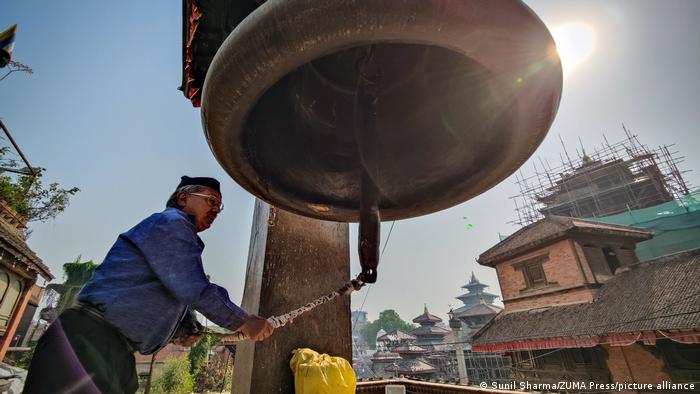 Un hombre hace sonar una gran campana en el lugar de reconstrucción de la plaza Hanumandhoka Durbar en Katmandú, Nepal, que conmemoró este año el séptimo aniversario del devastador terremoto de Gorkha que mató a casi 9.000 personas y dejó a millones sin hogar. 
