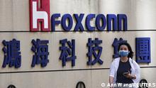 9.11.2022, Taipeh, Taiwan, A woman walks past the logo of Foxconn outside the company's building in Taipei, Taiwan November 9, 2022. REUTERS/Ann Wang