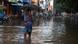 A man walks through a flooded street during a heavy monsoon rainfall in Chennai