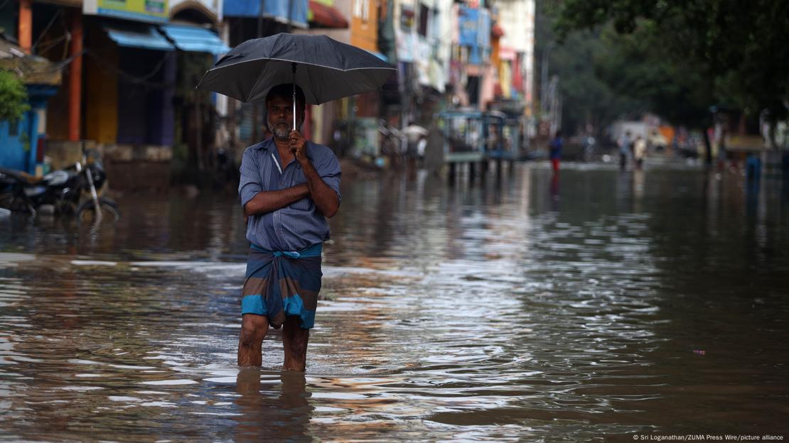 A man walks through a flooded street during a heavy monsoon rainfall in Chennai