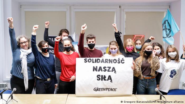 Młodzi polscy działacze na rzecz klimatu trzymający znak Greenpeace podnoszą pięści, Warszawa, grudzień 2020