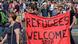 Демонстрация в поддержку беженцев в Дрездене, 2015 год. Мужчины держат красный плакат с надписью "Беженцы, добро пожаловать". Демонстрация в поддержку беженцев в Дрездене, 2015 год. Мужчины держат красный плакат с надписью "Беженцы, добро пожаловать".