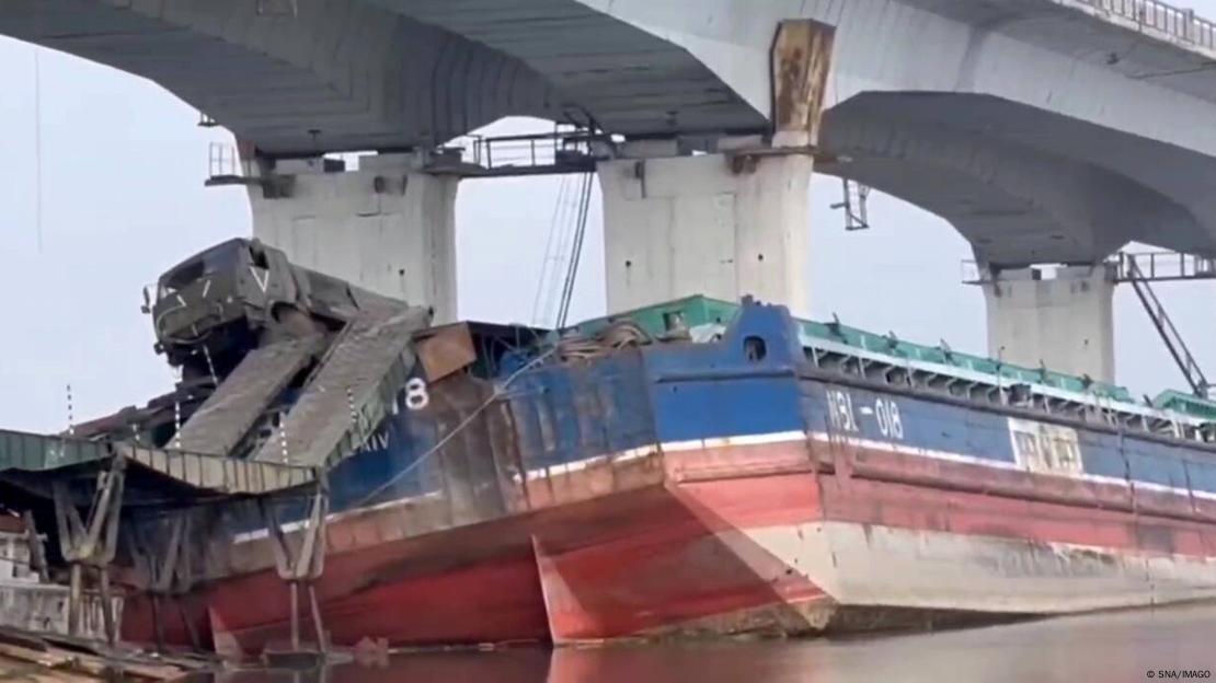 Passagem improvisada com uma balsa sob uma ponte avariada sobre o rio Dnipro para a passagem de veículos militares russos