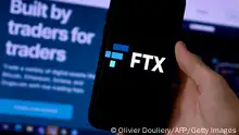 This illustration photo shows a smart phone screen displaying the logo of FTX, the crypto exchange platform, with a screen showing the FTX website in the background in Arlington, Virginia on February 10, 2022. - Sam Bankman-Fried donned a suit and tie this week, abandoning his preferred hoodie and dark T-shirt for a hearing before US Senators. The lawmakers had summoned the 29-year-old multi-billionaire on Wednesday to discuss the regulation of digital assets in his capacity as co-founder and CEO of the cryptocurrency exchange platform FTX (Photo by OLIVIER DOULIERY / AFP) (Photo by OLIVIER DOULIERY/AFP via Getty Images)