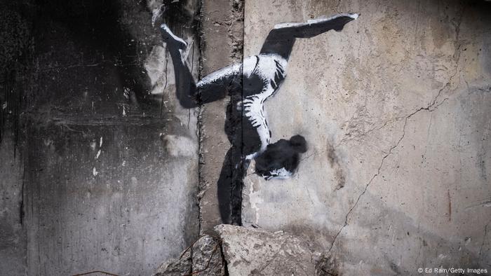 Banksy Streetart auf zerstörtem Haus in Borodjanka: Ein Mädchen macht Handstand auf Trümmern