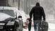 A man carrying a suitcase on a snowed-in street A man carrying a suitcase on a snowed-in street