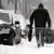 A man carrying a suitcase on a snowed-in street