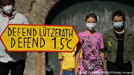 Greta Thunberg, Luisa Neubauer und Landwirt Eckhardt Heukamp, vor ihnen ein Schild: Defend Lützerath, defend 1,5 Grad Celsius 