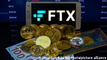 FTX logo with crypto coins with 100 Dollar bill are displayed for illustration. FTX has filed for bankruptcy in the US, seeking court protection as it looks for a way to return money to users. (Photo illustration by Jonathan Raa/NurPhoto)