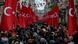 Pedestrians walk through Istiklal Street in Istanbul, with the street lined with red Turkish flags Pedestrians walk through Istiklal Street in Istanbul, with the street lined with red Turkish flags