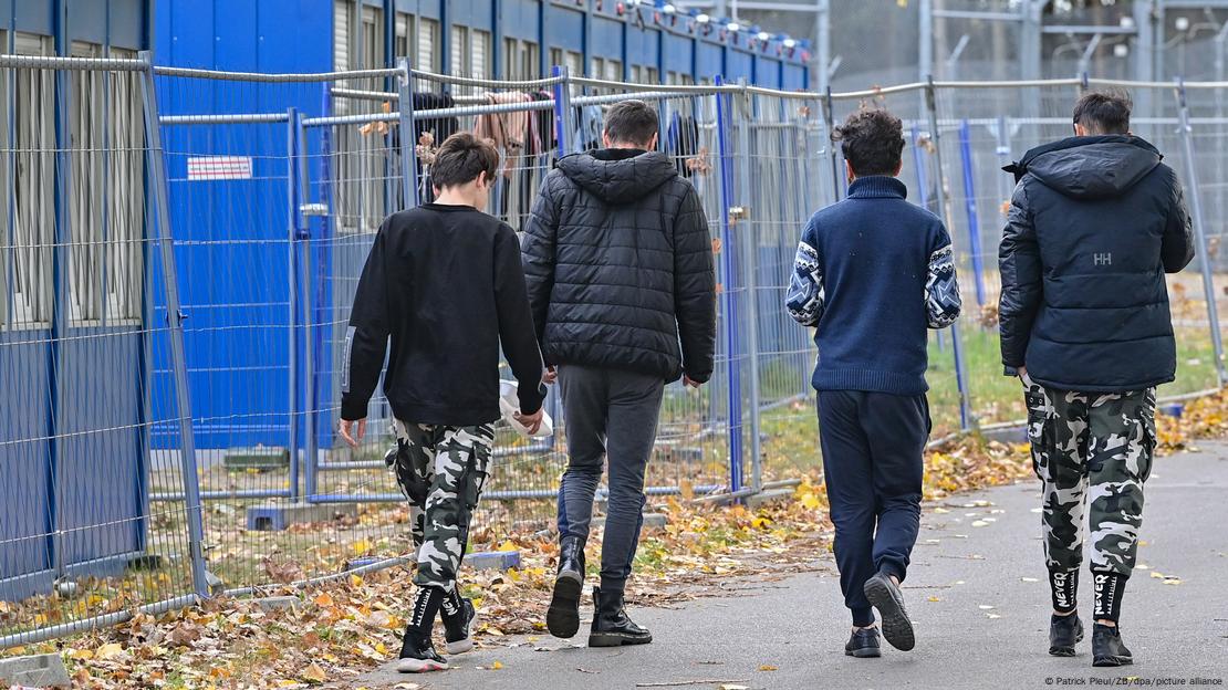 Izbjeglice snimane s leđa hodaju unutar Središnje ustanove za prijam tražitelja azila u Brandenburgu