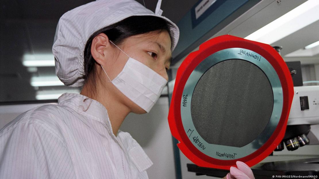 Infineon'a ait çip fabrikasında bir ürünü inceleyen kadın çalışan