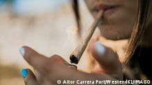 Young woman igniting marijuana cigarette outdoors model released Symbolfoto ACPF01230