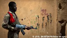 TOPSHOT - Malian army paratrooper Soumaila Coulibaly, aged 26, poses with an AK-47 assault rifle on February 25, 2013 in Gao, some 1,200 kilometres (745 miles) north of Bamako. After recapturing the north's cities from the Al Qaeda groups that had controlled them since April 2012, the six-week-long French-led offensive took the fight to the retreating Islamist insurgents' toughest desert bastions. AFP PHOTO / JOEL SAGET (Photo by Joël SAGET / AFP) (Photo by JOEL SAGET/AFP via Getty Images)
