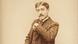Marcel Proust in a suit, arm raised, looking into the camera. Marcel Proust in a suit, arm raised, looking into the camera.