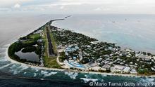 FUNAFUTI, TUVALU - NOVEMBER 28: An aerial view of downtown and the airport runway, between the Pacific Ocean (L) and lagoon (R), on November 28, 2019 in Funafuti, Tuvalu. The low-lying South Pacific island nation of about 11,000 people has been classified as ‘extremely vulnerable’ to climate change by the United Nations Development Programme. The world’s fourth-smallest country is struggling to cope with climate change related impacts including five millimeter per year sea level rise (above the global average), tidal and wave driven flooding, storm surges, rising temperatures, saltwater intrusion and coastal erosion on its nine coral atolls and islands, the highest of which rises about 15 feet above sea level. In addition, the severity of cyclones and droughts in the Pacific Island region are forecast to increase due to global warming. Some scientists have predicted that Tuvalu could become inundated and uninhabitable in 50 to 100 years or less if sea level rise continues. The country is working toward a goal of 100 percent renewable power generation by 2025 in an effort to curb pollution and set an example for larger nations. Tuvalu is also exploring a plan to build an artificial island. (Photo by Mario Tama/Getty Images)