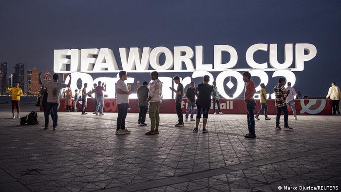 Personas ante un cartel luminoso de la FIFA en Qatar.