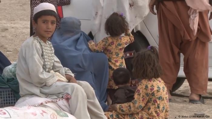 A la frontière entre Pakistan et Afghanistan, quatre enfants afghans attendent dehors avec une femme voilée