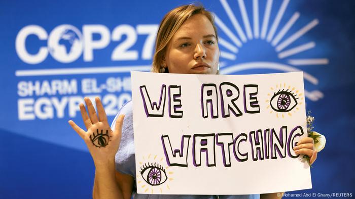 Klimaschutz-Aktivistin mit Schild: We are watching