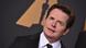Michael J. Fox mit schräggelegtem Kopf, im Hintergrund ein Oscar-Emblem Michael J. Fox mit schräggelegtem Kopf, im Hintergrund ein Oscar-Emblem