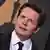 Michael J. Fox mit schräggelegtem Kopf, im Hintergrund  ein Oscar-Emblem
