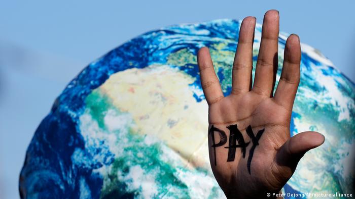 一位气候保护抗议者在埃及COP27会议期间举起写着“支付”的手心