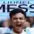 Man, shouting,  holds up a blue scarf with the name Lionel Messi