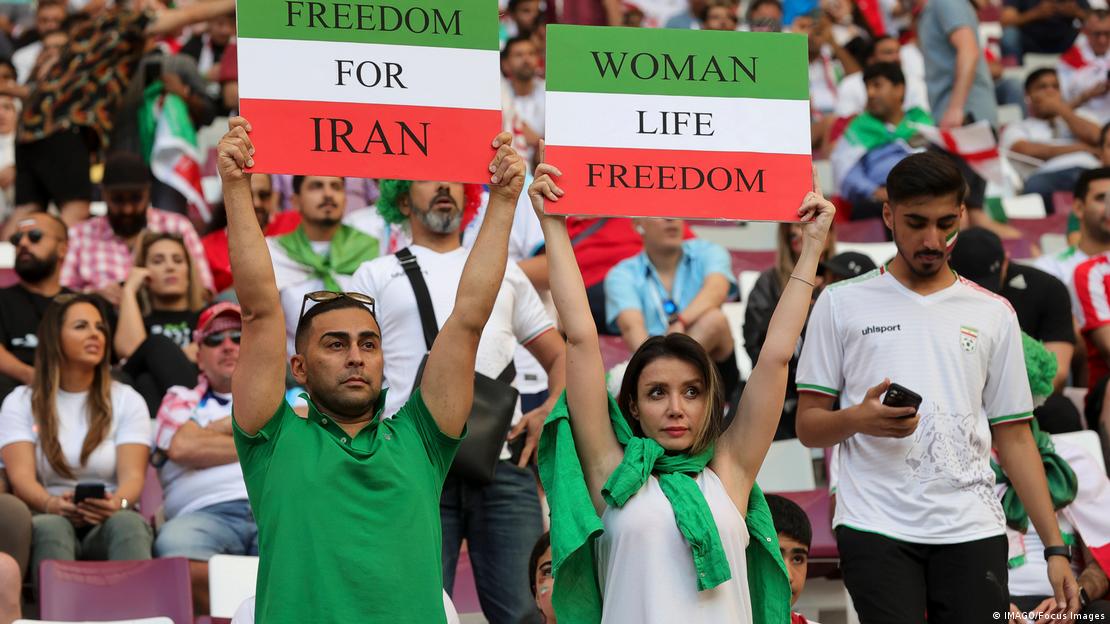 Iran fans hold Freedom For Iran and Women Life Freedom placards before the 2022 FIFA World Cup Group B match at Khalifa International Stadium