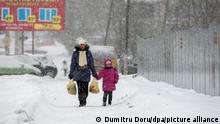 epa04048565 A woman walks with a girl during snowfall in downtown Chisinau, Moldova, 30 January 2014. According to meteorologists, the temperature fell to minus 18 degrees Celsius, after a long warm period with temperatures. EPA/DUMITRU DORU ++ +++ dpa-Bildfunk +++