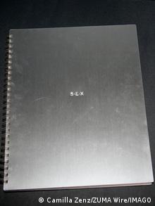 Silbernes Buchcover von Madonna Buch Sex, das die drei Buchstaben eingeprägt zeigt. Den Band hält eine Spiralbindung zusammen.