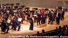 Zwei Aktivisten stehen auf der Bühe der Elbphilharmonie. Kurz vor Beginn eines Konzerts in der Elbphilharmonie haben Klimaaktivisten der «Letzten Generation» sich am Mittwochabend an einem Dirigentenpult festgeklebt. (zu dpa: «Klimaaktivisten kleben sich in Elbphilharmonie an Dirigentenpult fest») +++ dpa-Bildfunk +++