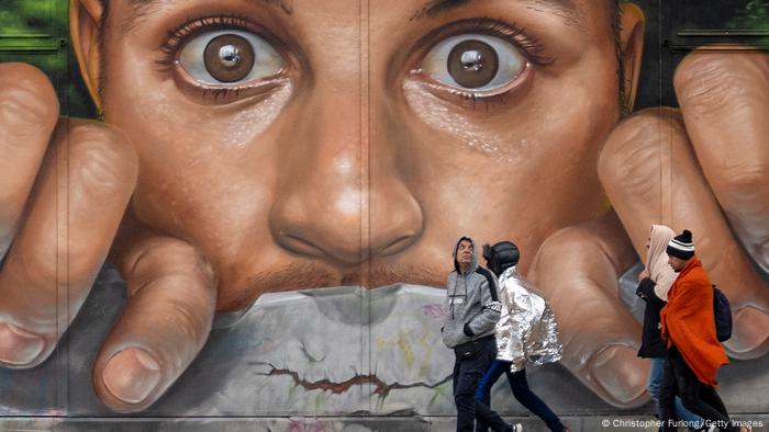 Migranten vor einem Wandbild des Künstlers Braga Last1 in Calais, Frankreich: