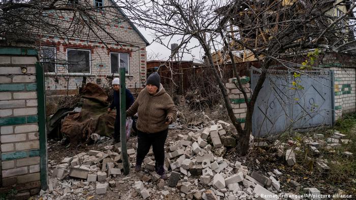 Zwei Männer an einer zerstörten Mauer vor einem Haus in Cherson