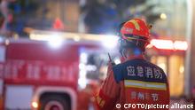 Un operario de los servicios de rescate habla por radio con un camión de bomberos desenfocado al fondo.