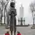 A imagem mostra a estátua de uma menina em frente a um grande monumento no Memorial do Genocídio do Holodomor em Kiev, na Ucrânia.