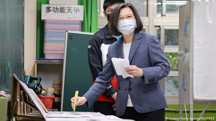 Tsai, con tapabocas, ingresa su voto en la urna mirando a cámara.