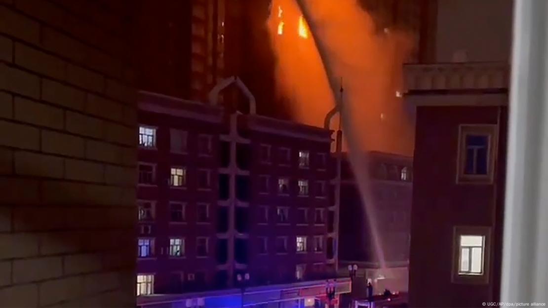 Bombeiros tentam conter chamas em prédio. Foto noturna