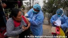 A healthcare worker gives resident Marlith Fasabi doses of the flu vaccine and Moderna vaccine for COVID-19 during a door-to-door vaccination campaign in the Ticlio Chico neighborhood on the outskirts of Lima, Peru, on the first official day of winter, Tuesday, June 21, 2022. Temperatures in the capital are the lowest in 25 years, according to the National Service of Meteorology and Hydrology of Peru. (AP Photo/Martin Mejia)