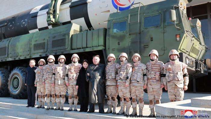 Der nordkoreanische Machthaber Kim Jong Un posiert mit Tochter und Soldaten auf einem militärischen Stützpunkt. Im Hintergrund eine Interkontinentalrakete.