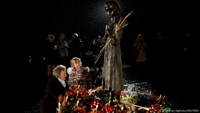Una mujer y una niña ponen velas en el monumento a las víctimas de la hambruna.