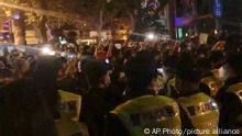In this image from video obtained by The Associated Press, police, foreground, watch protesters in Shanghai on Saturday, Nov. 26, 2022. Protests against China’s restrictive COVID measures appeared in a number of cities Saturday night, in displays of public defiance fanned by anger over a deadly fire in the western Xinjiang region. (AP Photo)