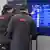 Two ÖBB workers point at screen with train schedule on it