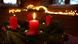 Ein Adventskranz mit roten Kerzen, eine davon brennt. Ein Adventskranz mit roten Kerzen, eine davon brennt.