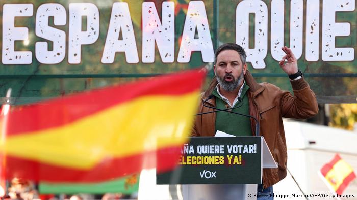 Con un letrero detrás en el que se lee España quiere votar. Elecciones ya, el político gesticula durante su discurso mientras se agitan banderas de España.